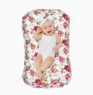 Baby lying on a floral-patterned cushion with a white background