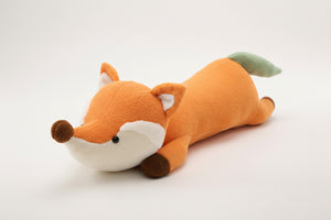 Plush fox toy on a textured surface with a magazine rack in the background