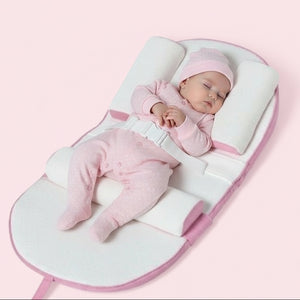 A baby lying on a green and white anti-reflux and anti-roll baby lounger bed.
