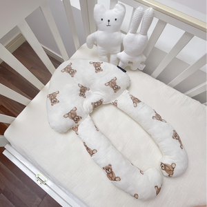 A baby lying on a white, solid patterned sleep pillow designed for infants.