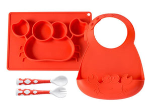 Red silicone baby tray with compartments, red bib with a cat design, red and white spoons, and red and white fork on a white background.