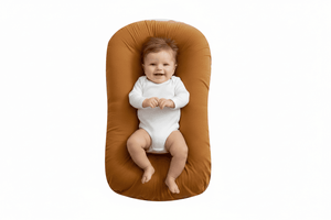 Baby lying on a brown baby lounger with a white background
