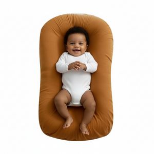 Baby lying on a brown baby lounger with a white background