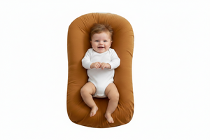Baby lying on a brown baby lounger with a white background