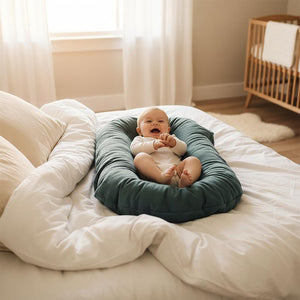 Baby lying on a teal cushion with a plain background
