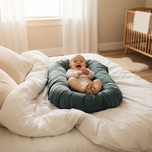 Baby lying on a teal cushion with a plain background