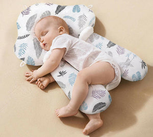 A baby lying on a white, solid patterned sleep pillow designed for infants.