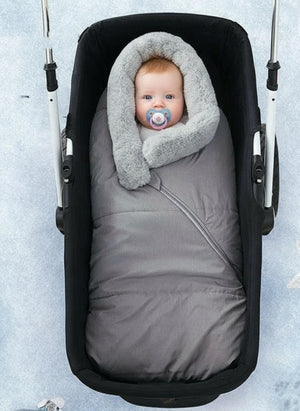 A baby sleeping bag with a gray color and a removable fur collar, zipped into a stroller, keeping the baby warm and protected.