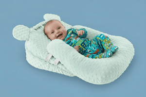 Baby in a white bear-shaped baby nest on a blue background