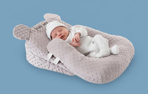 Gray baby support pillow with U-shaped design on a light gray background