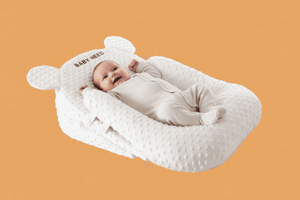 Baby lying in a white baby nest with a bear-shaped headrest on an orange background
