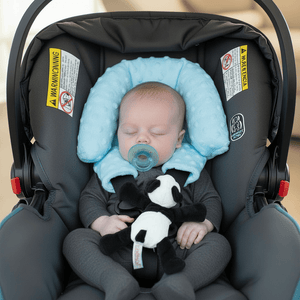 Baby sleeping in a car seat with a blue head support and panda toy.