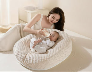 Woman feeding a baby with a bottle on a textured cushion