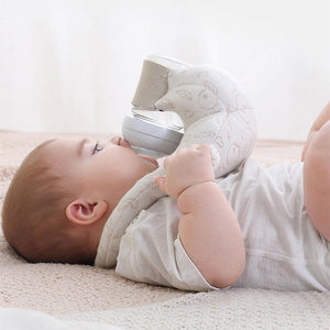 A baby lying on a hands-free self-feeding pillow, holding a bottle.