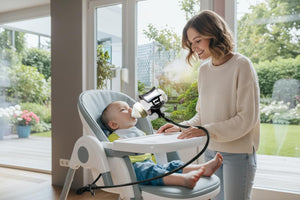 Baby in a highchair with a hands free baby bottle holder