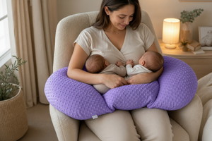 Woman breastfeeding two babies using a purple nursing pillow in a cozy room.
