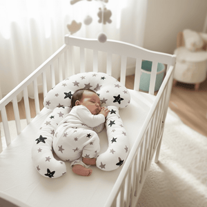 Baby sleeping in a crib with a star-patterned body pillow