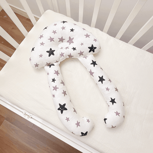 A baby lying on a white, solid patterned sleep pillow designed for infants.