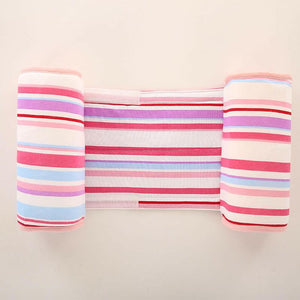 A baby lying on a gray anti-roll safety support pillow with red trim.