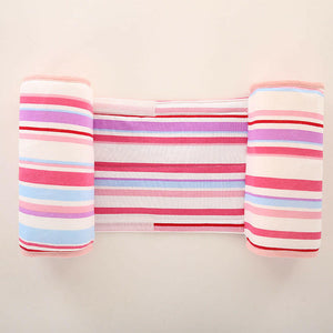A baby lying on a gray anti-roll safety support pillow with red trim.
