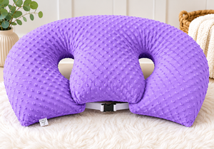 Purple U-shaped pillow on a white surface with a blurred background