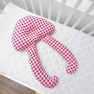 A baby lying on a white, solid patterned sleep pillow designed for infants.
