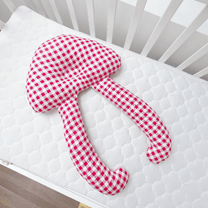 A baby lying on a white, solid patterned sleep pillow designed for infants.
