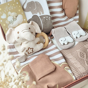 Collection of baby items including a plush elephant toy, rattle, and soft blanket with baby-themed designs.