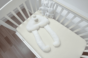 A baby lying on a white, solid patterned sleep pillow designed for infants.