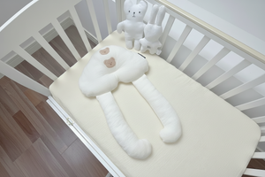 A baby lying on a white, solid patterned sleep pillow designed for infants.
