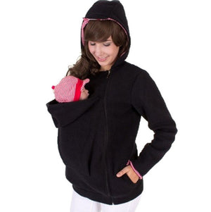 Woman wearing a black hoodie with a baby carrier on a white background