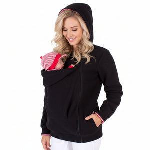 Woman wearing a black hoodie with a baby carrier on a white background