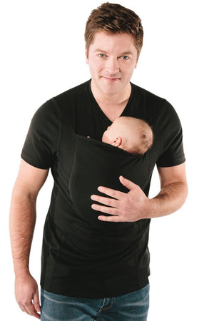 Man wearing a black t-shirt holding a baby in a sling against a white background