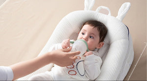 Baby lying on a white cushion with text about comfort and size.