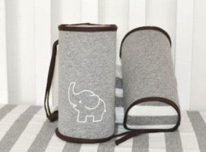 A baby lying on a safety support pillow designed to prevent rolling over, featuring gray color with red trim and a white embroidered design.