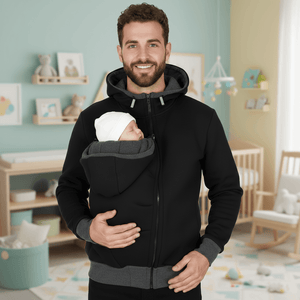Man holding a baby in a black and gray baby carrier in a nursery.