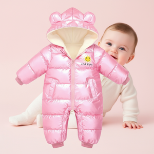 Baby wearing a pink puffer snowsuit with a hood on a pink background