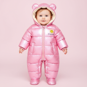 Baby wearing a pink puffer snowsuit with bear ears on a pink background