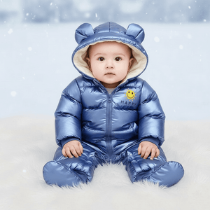 Baby in a blue snowsuit with bear ears sitting on a snowy background