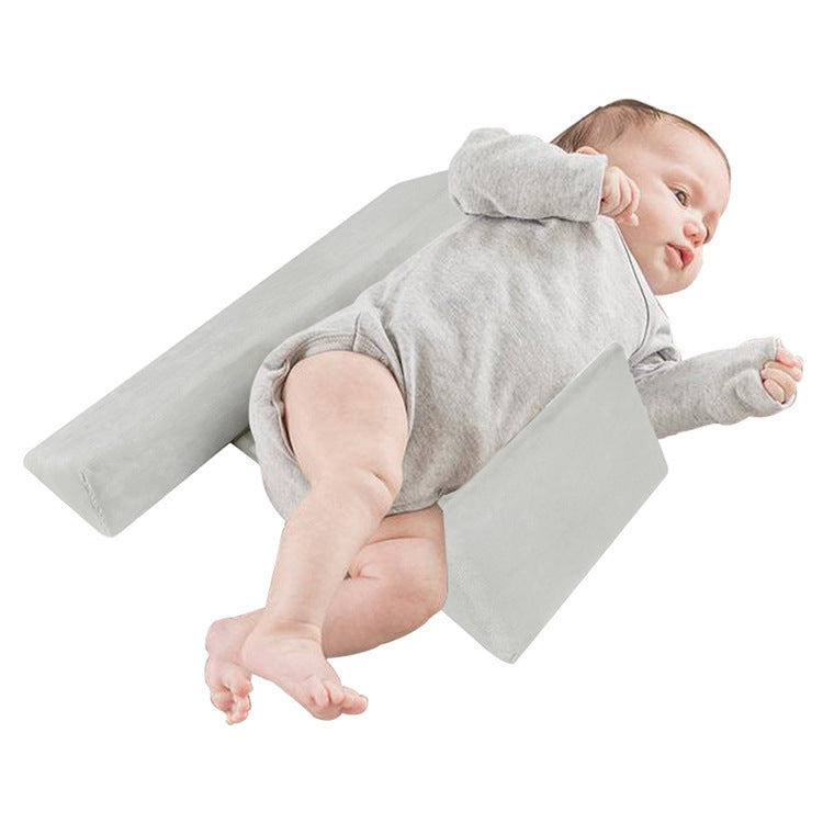 Baby lying on a gray wedge-shaped product on a white background
