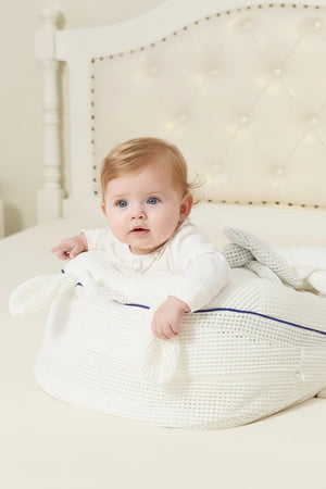 Baby in a white textured basket with a soft blanket