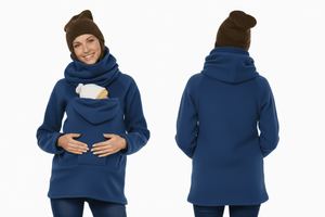 Woman wearing a blue hoodie with a front pocket, brown beanie, and holding a baby in a carrier on a white background.