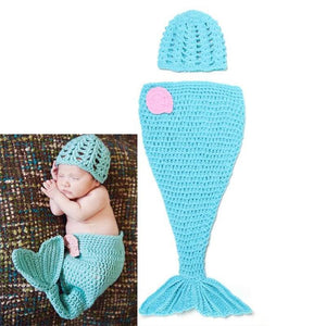 Crocheted mermaid tail and hat set with a baby wearing it on a white background.