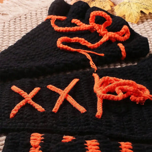 Black gloves with orange embroidered letters on a textured surface