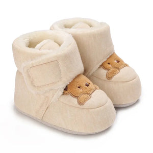 Beige baby booties with bear face design on a white background