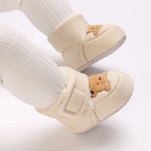 Beige baby shoes with bear design on a white background