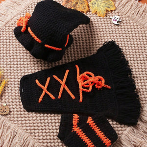 Black and orange crocheted gloves on a textured surface with autumn leaves.