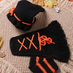 Black and orange crocheted gloves on a textured surface with autumn leaves.