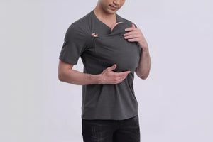 Man wearing a gray t-shirt with a small logo, holding a baby in a sling against a white background