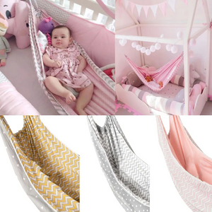 Baby in a pink hammock with various patterns and toys.